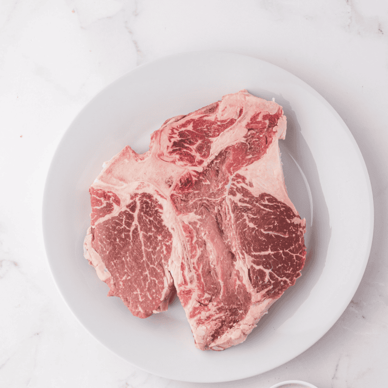 Two raw porterhouse steaks resting at room temperature and patted dry with paper towels