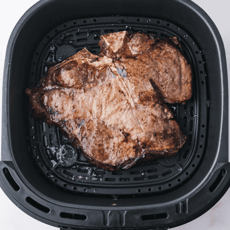 Instant-read thermometer in the thickest part of an air fryer porterhouse steak reading 130&deg;F