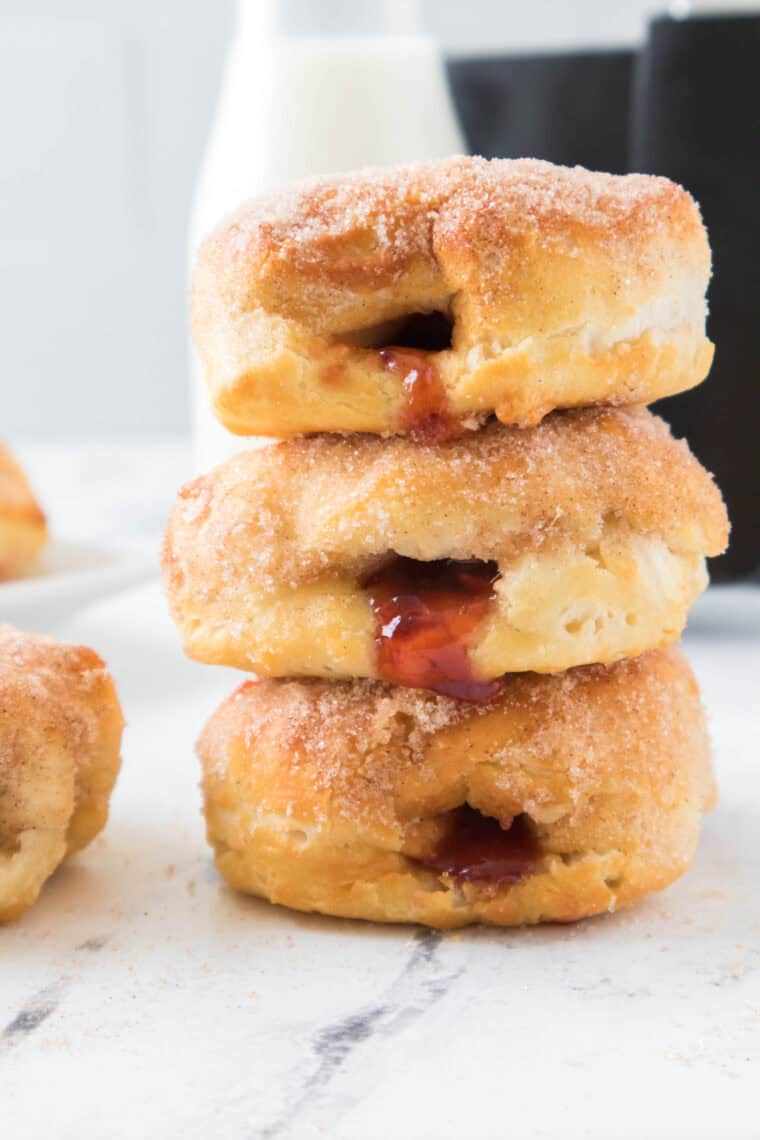 Side view of stacked air fryer jelly donuts showing strawberry filling and cinnamon-sugar coating