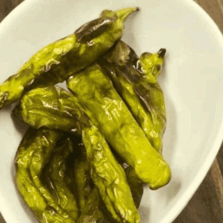 Blistered Benihana-style shishito peppers, golden and seasoned, served on a plate.