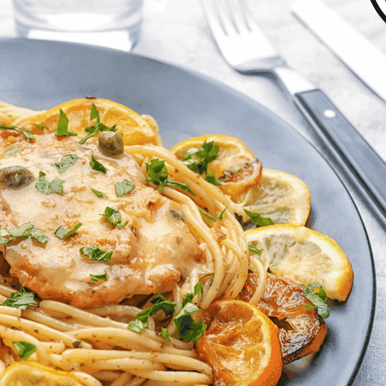 Plate of Carrabba’s Chicken Piccata featuring golden chicken breasts topped with lemon-caper sauce and garnished with fresh parsley.