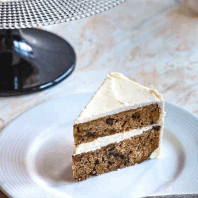 Layered carrot cake cheesecake topped with creamy frosting and chopped walnuts.