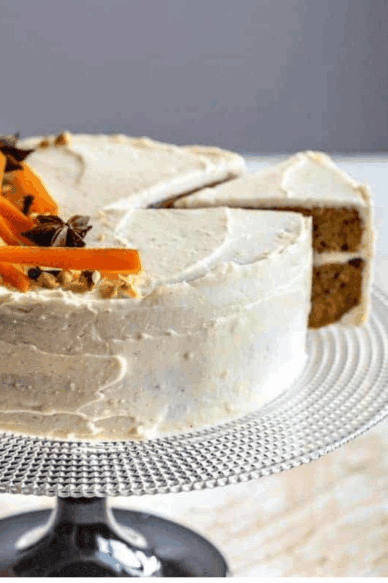 Slice of Copycat Cheesecake Factory Carrot Cake Cheesecake with cream cheese frosting and layered filling on a white plate.
