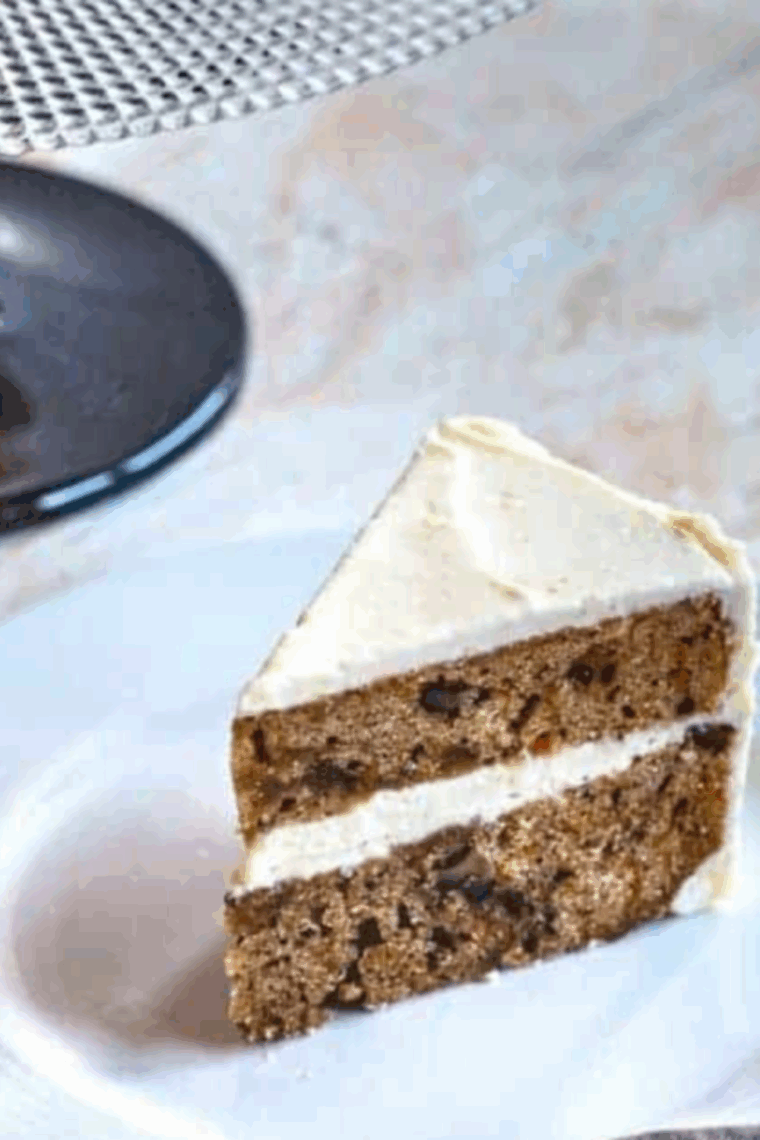 Slice of Carrot Cake Cheesecake with spiced carrot cake layers and creamy cheesecake filling.