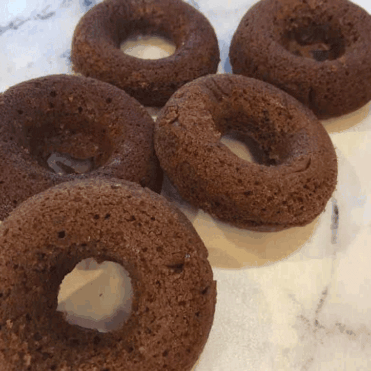 Cooled homemade donuts being removed from the mold before preparing the chocolate glaze.