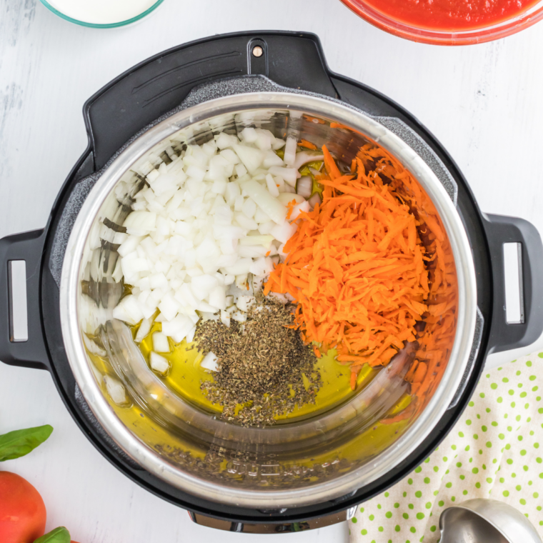 Diced onion, shredded carrots and dried basil added to hot olive oil in an Instant Pot insert