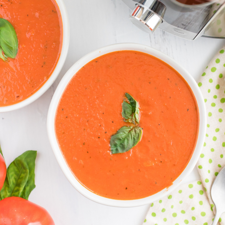 Creamy copycat Nordstrom tomato basil soup in a white bowl with a swirl of cream and fresh basil