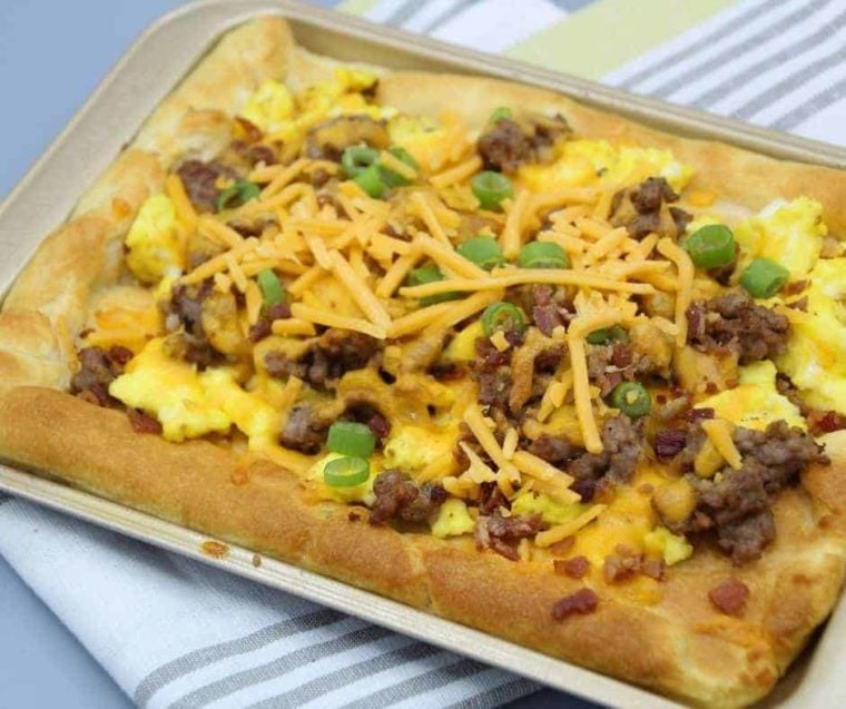 crescent roll breakfast pizza on a baking pan with a striped linen background