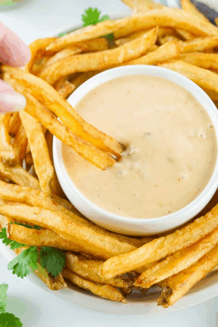 Small bowl of creamy Bojangles-style honey mustard sauce with crispy chicken tenders on the side