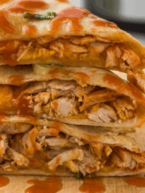 Instant Pot Buffalo Chicken Quesadillas on a plate with melted cheese and a side of dipping sauce.
