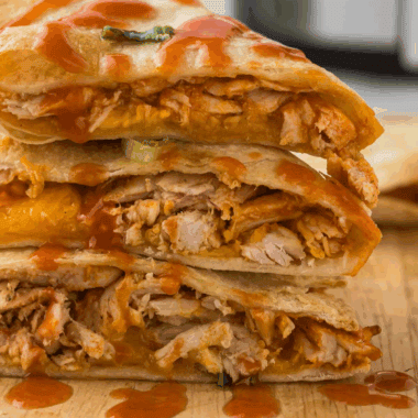 Instant Pot Buffalo Chicken Quesadillas on a plate with melted cheese and a side of dipping sauce.