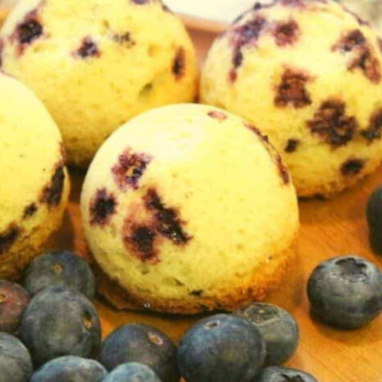 Close-up of fluffy and moist Instant Pot Blueberry Muffins on a cooling rack, showing their vibrant blue berries.