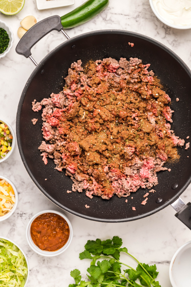 Ground beef browning in a skillet with taco seasoning for air fryer taco pie