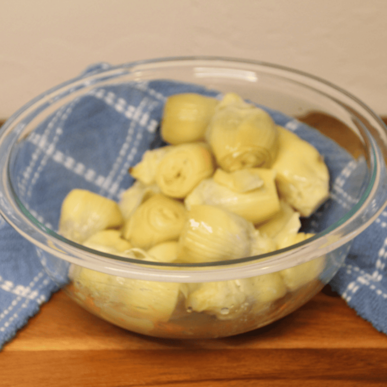 Ingredients needed for making artichoke dip in bowl. Placed on table.