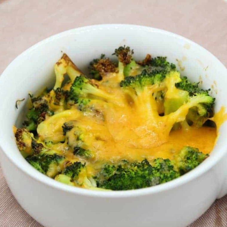 Close-up of roasted broccoli florets with melted cheese sauce