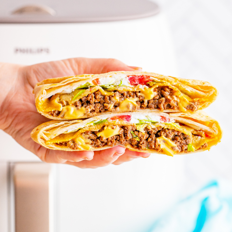Golden brown crunchwrap supreme cooked in air fryer with visible layers of beef, cheese sauce, and fresh toppings.