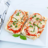 Sliced air fryer French bread pizza with melted mozzarella and fresh basil on a wooden cutting board