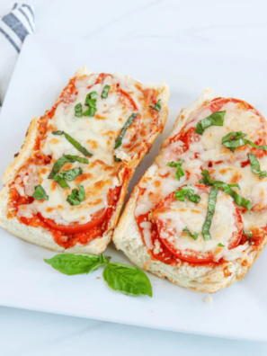 Sliced air fryer French bread pizza with melted mozzarella and fresh basil on a wooden cutting board