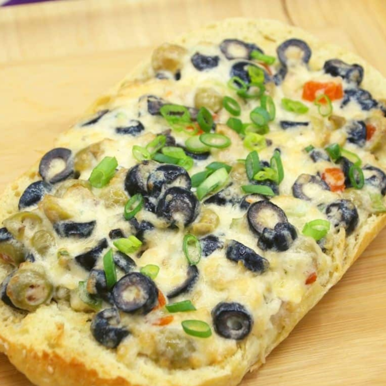 Close-up of golden brown Air Fryer Olive Cheese Bread, showcasing melted cheese and olive pieces.