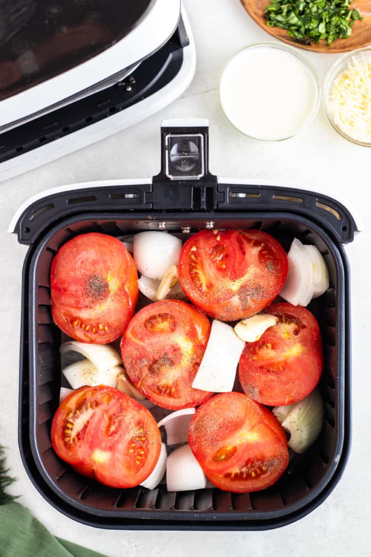 overhead: tomatoes and onions in the basket to make air fryer roasted salsa