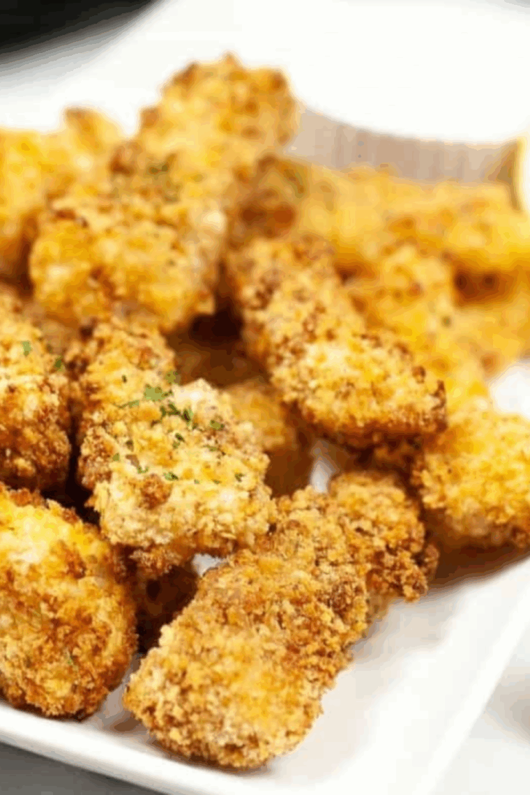 Plate of crispy, golden Captain D’s style fish sticks served with tartar sauce and lemon wedges.