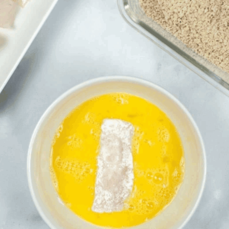 Placing the fish sticks into the egg mixture.