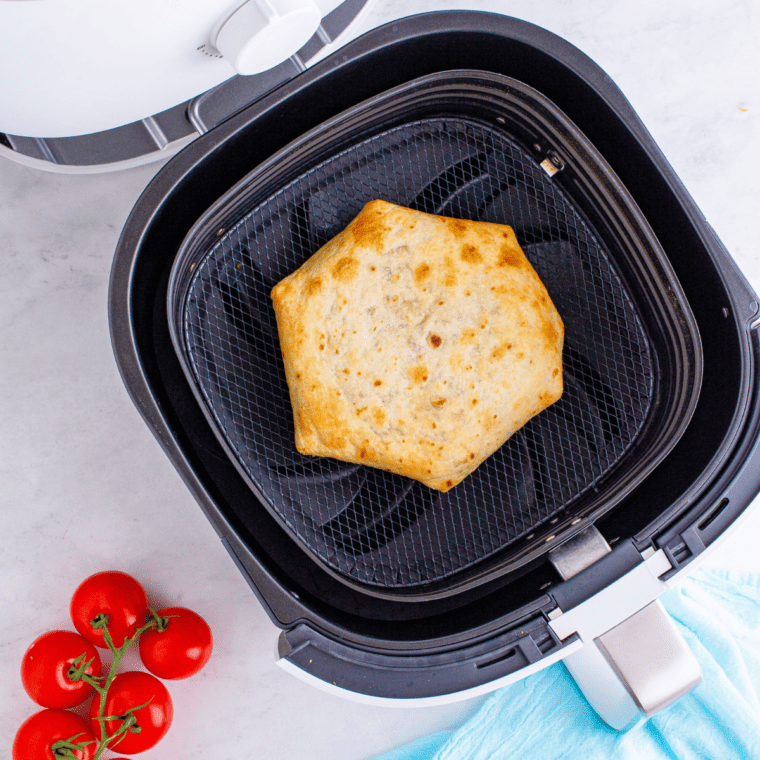 overhead process shot: folded crunchwrap supreme placed seam side down in air fryer after cooking