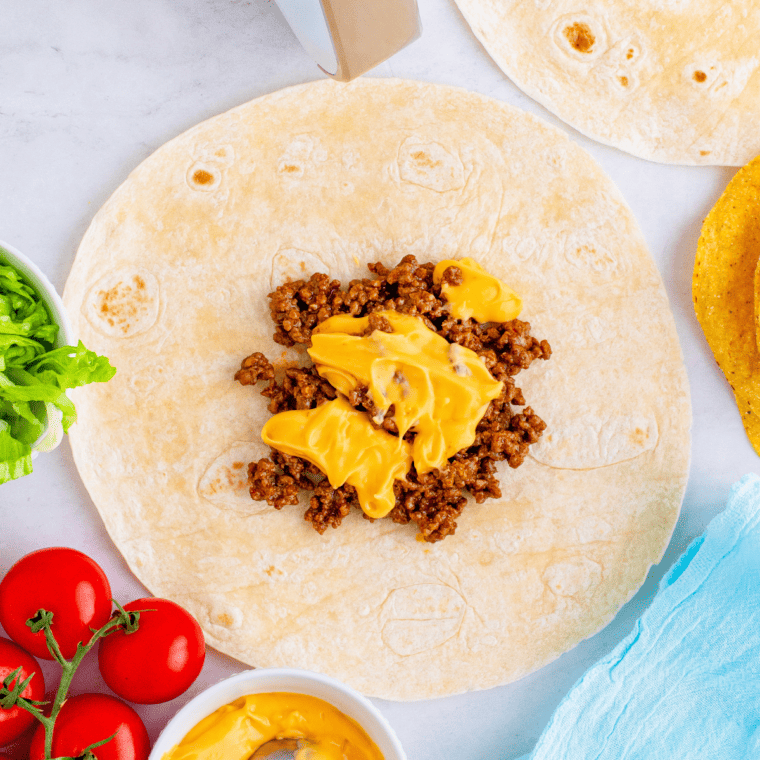 overhead process shot: ground beef and nacho cheese added to large tortilla