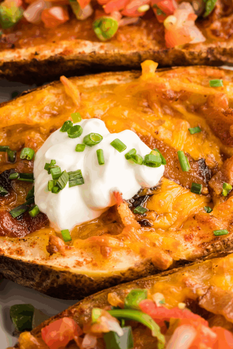 Golden brown Texas Roadhouse tater skins topped with melted cheese, bacon, and green onions on a serving platter.
