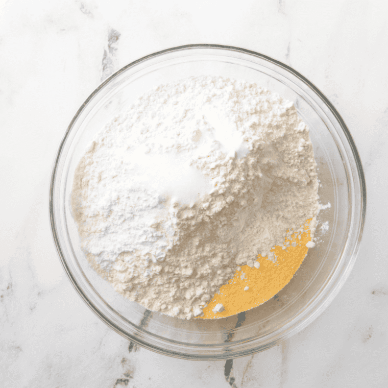 Mixing dry ingredients in one bowl and whisking wet ingredients in another bowl to prepare batter for blueberry lemon cornbread.