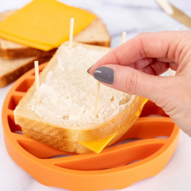 Grated cheddar cheese layered between two buttered slices of bread for a grilled cheese sandwich