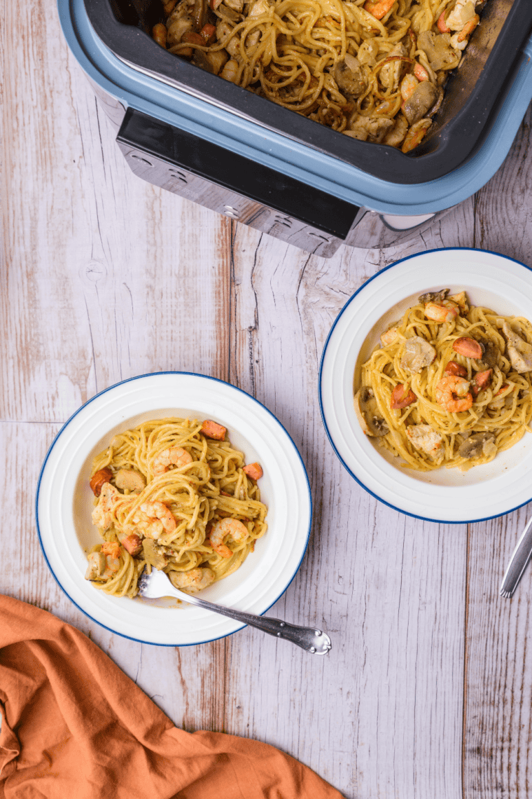 Close-up of fettuccine alfredo with grilled chicken and black pepper.