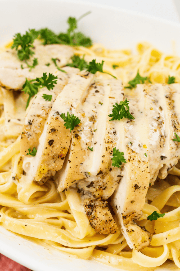 Close-up of fettuccine alfredo with grilled chicken and parmesan cheese.