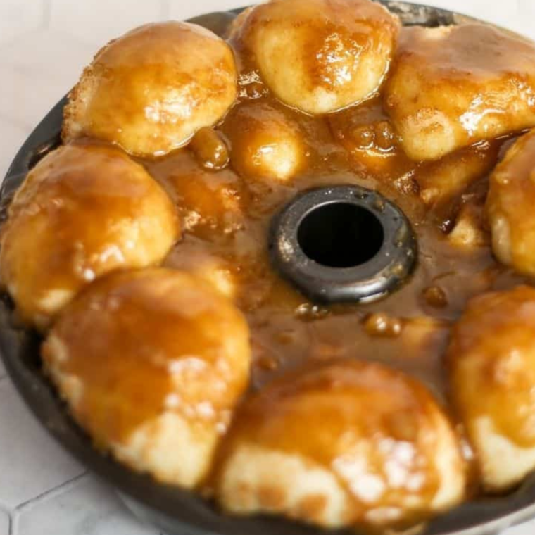 "Layering coated dough pieces in a baking pan with brown sugar and pecans"