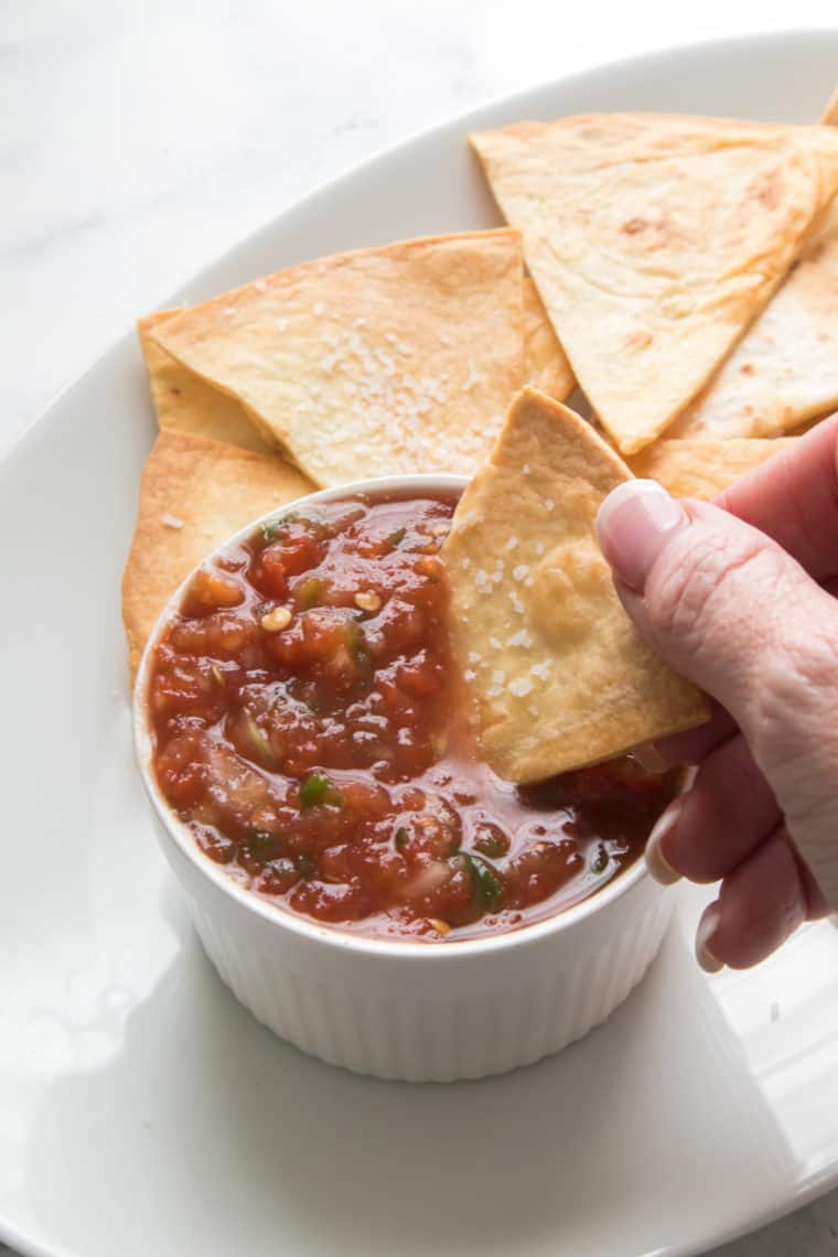 overhead closeup: a hand dipping a tortilla chip into air fryer salsa