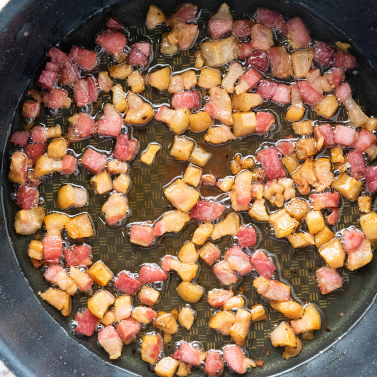 Cook the bacon: Chopped bacon frying in a non-stick skillet, garlic added at the end.