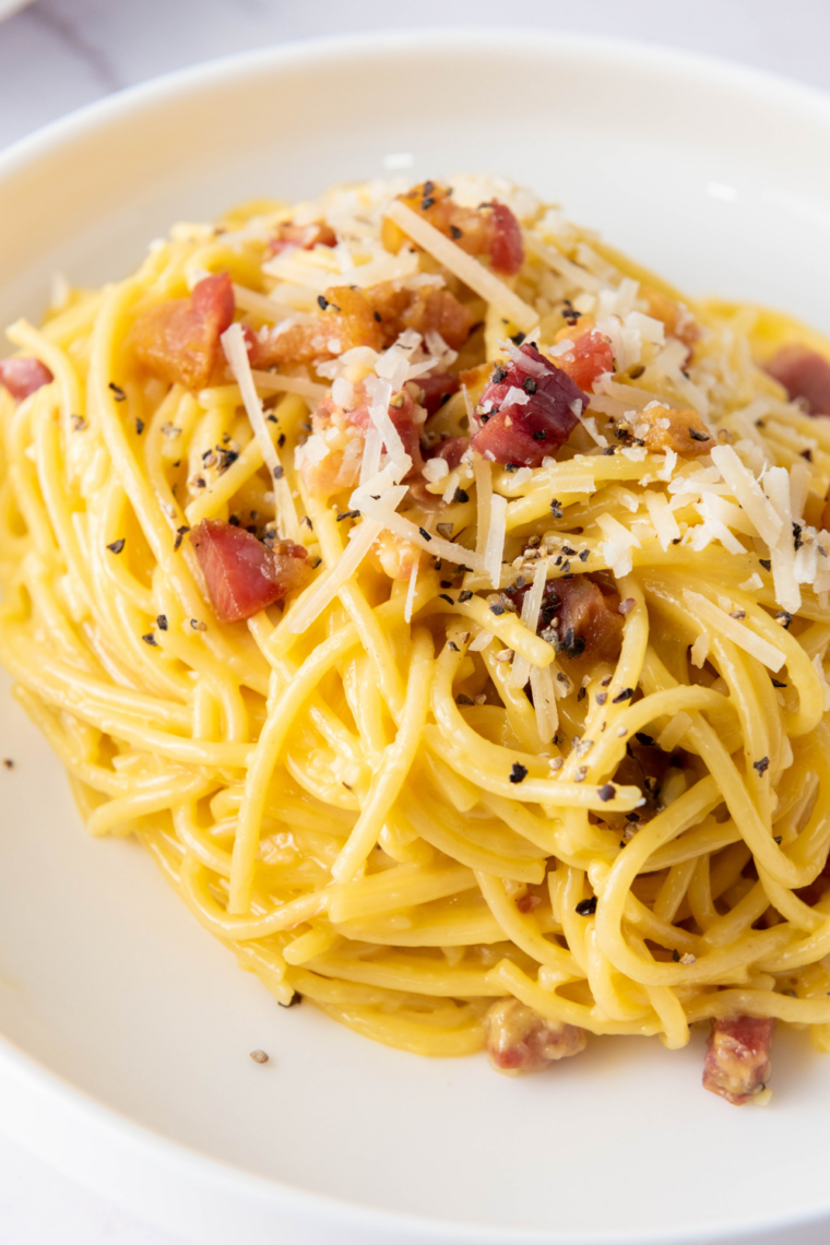 Plate of Slimming World friendly Spaghetti Carbonara with crispy bacon, creamy sauce, and sprinkled Parmesan.