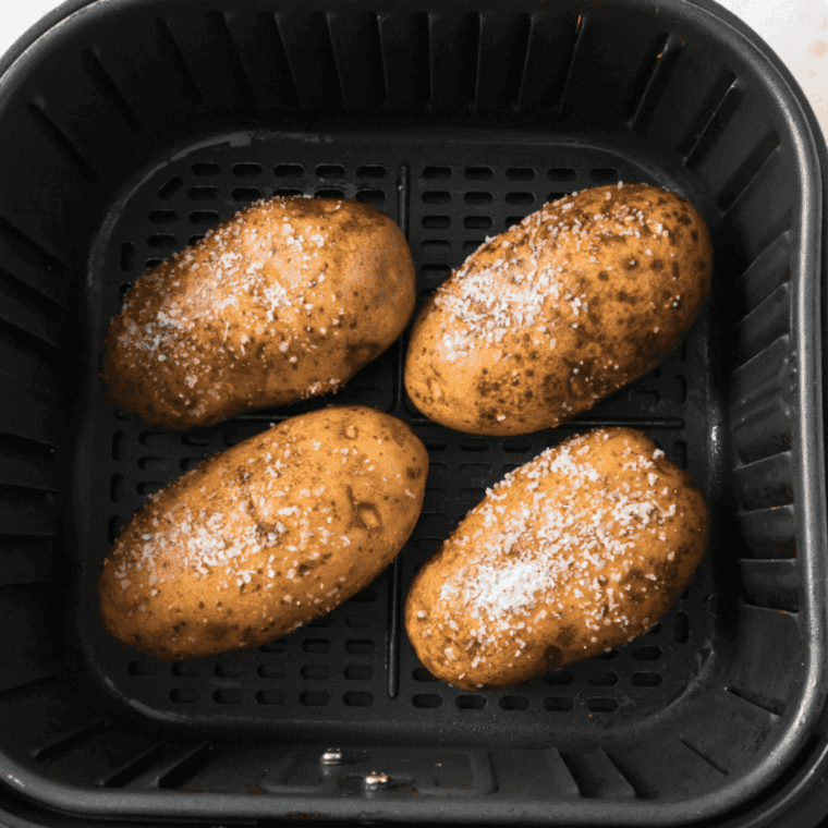 Season the baked potatoes and place them into the air fryer basket.