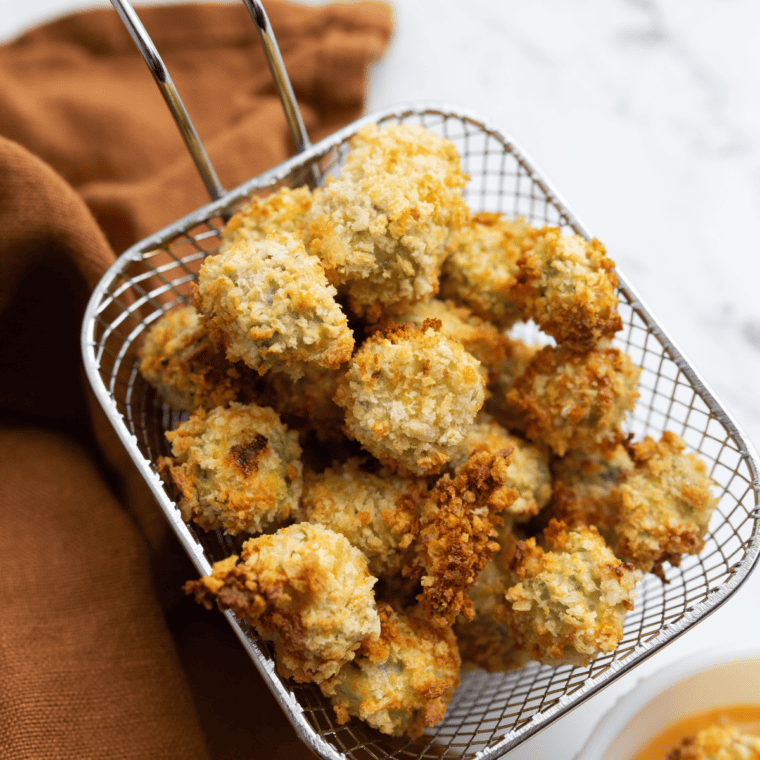 A plate of golden-brown, crispy air-fried okra pieces, garnished with a sprinkle of seasoning.