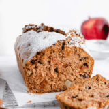 Sliced air fryer apple cranberry bread on a wooden board with fresh cranberries