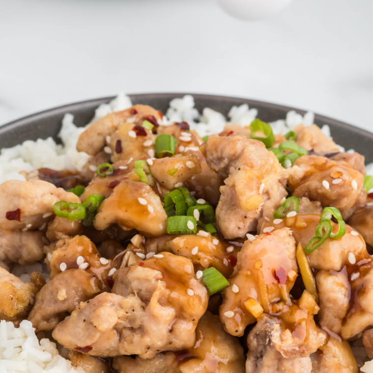 Close-up of tender Air Fryer Bourbon Chicken drizzled with sauce and served with steamed rice.