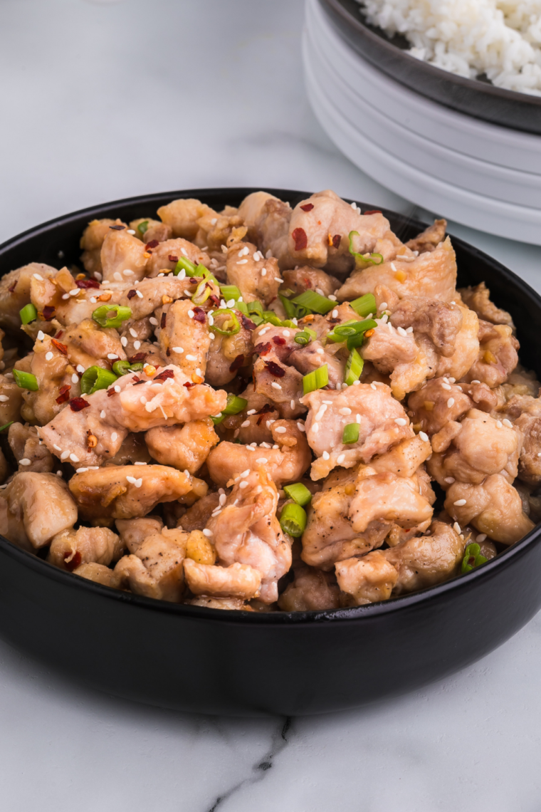  Plate of bourbon chicken over a bed of rice.