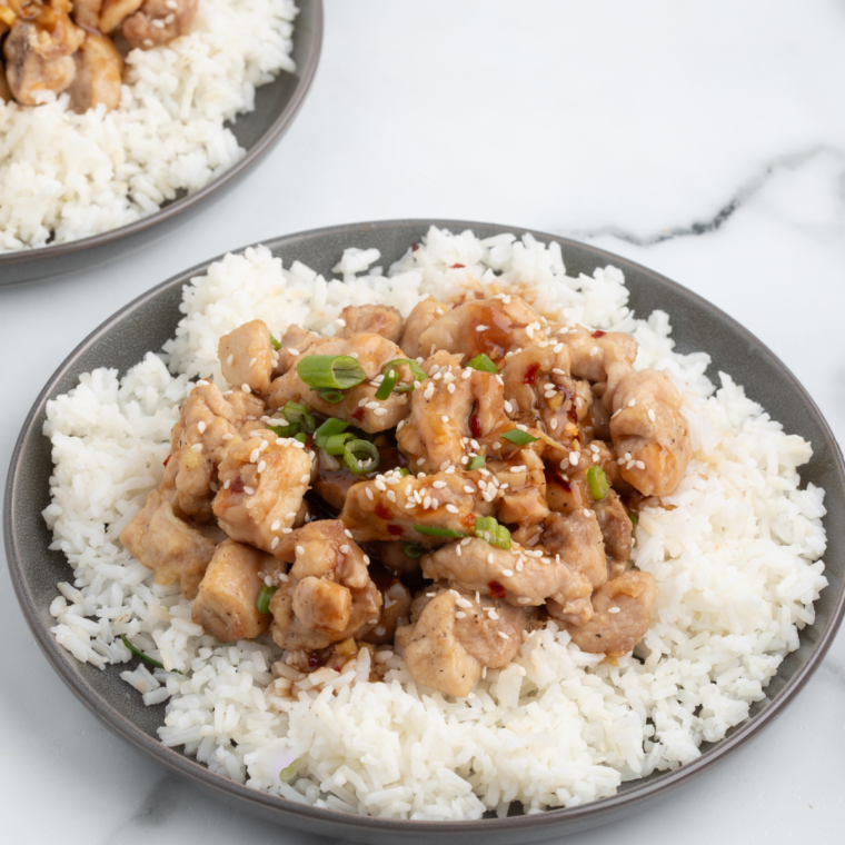 Air fryer basket with Bourbon Chicken cooking, showing the golden-brown color and crispy texture.