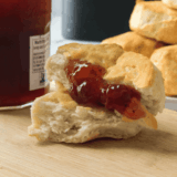 Golden brown air fryer canned biscuits in a basket, fluffy inside with a buttery finish.