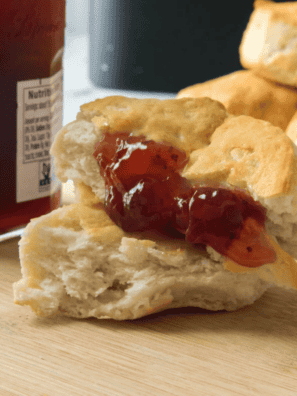 Golden brown air fryer canned biscuits in a basket, fluffy inside with a buttery finish.