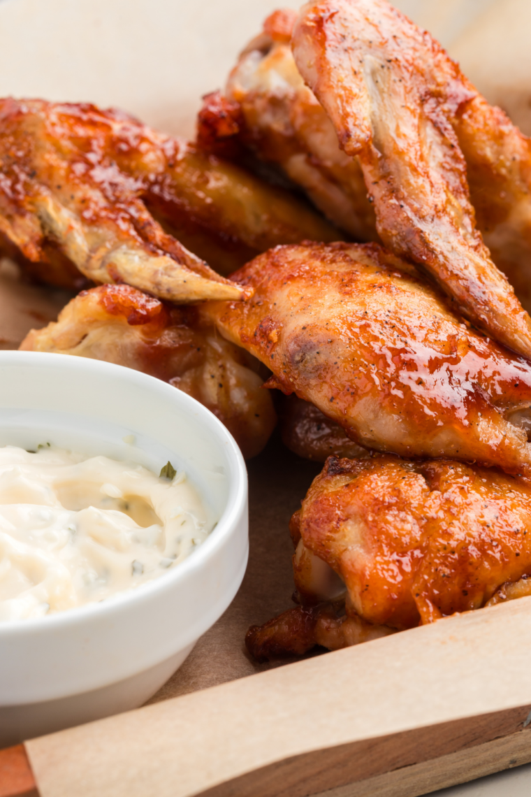 Air fryer basket filled with golden chicken wings glazed in honey barbecue sauce.