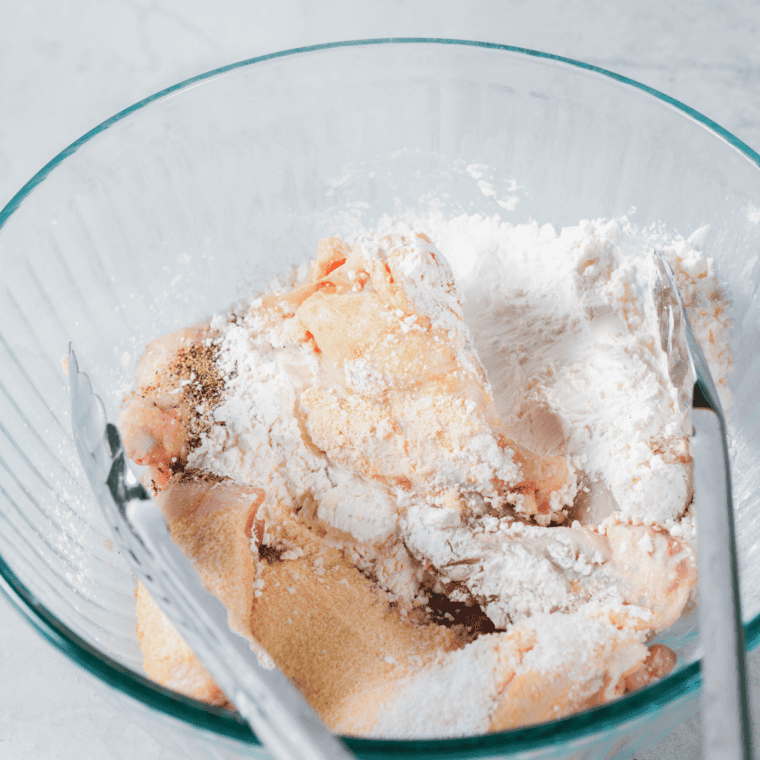 Raw chicken wings tossed with baking powder and spices in a bowl