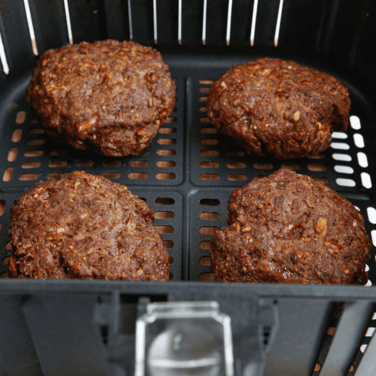 Cooked burgers in the air fryer basket.