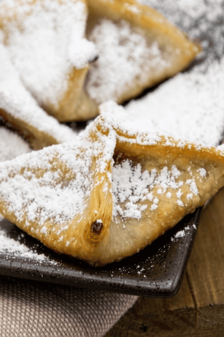 Plate of air fryer raspberry wontons topped with powdered sugar and fresh raspberries.