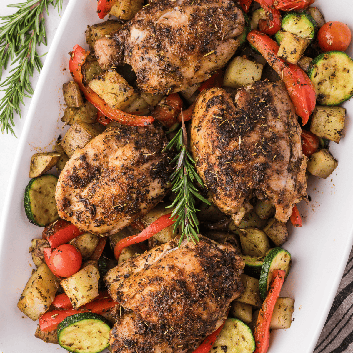 Juicy air-fried Tuscan chicken thighs topped with creamy sun-dried tomato and spinach sauce, served in a white dish.